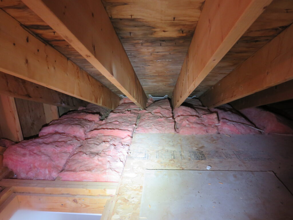 Dark staining on attic roof sheathing above insulation and ventilation baffles