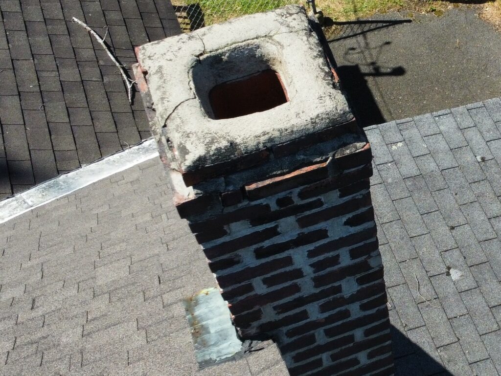 Uncapped chimney flue with a visible crack in the chimney crown